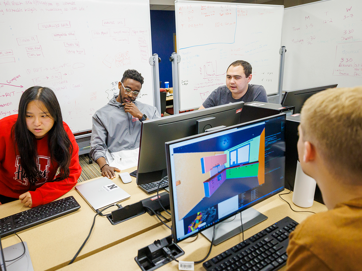 Students on computers with whiteboards in the background